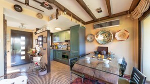 A spacious dining area with a glass table and chairs, a kitchen with green cabinets, and a patterned floor. - Rosa: A special holiday home in L´Escala (L'Escala)