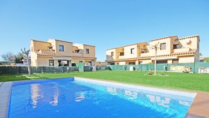 A swimming pool with a tiled deck, surrounded by a well-maintained lawn and a two-story building with a tiled roof. - Rosa: A special holiday home in L´Escala (L'Escala)