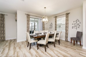 A dining room with a wooden table set for six, surrounded by six chairs.