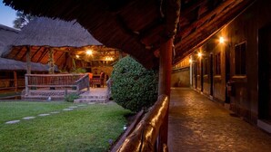 A rustic building with a thatched roof, a stone pathway, and a well-maintained lawn. - Ravine Lodge (Livingstone)