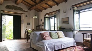 A cozy room with a white sofa, a patterned rug, and wooden beams on the ceiling. - Apartment the Crocodile Feel the Nature (Vicchio)