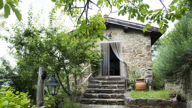 A stone house with a wooden staircase leading to a door with a curtain. - Apartment the Crocodile Feel the Nature (Vicchio)