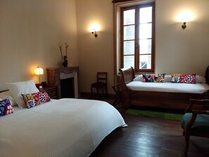A hotel room with two beds, a fireplace, a chair, and a window with shutters. - Chez Casimir (Cercy-la-Tour)