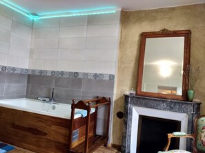 A bathroom with a freestanding bathtub, a wooden chair, a mirror, and a fireplace. - Chez Casimir (Cercy-la-Tour)