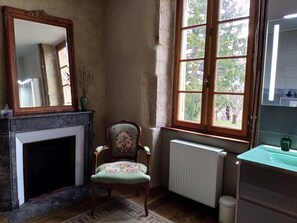A room with a fireplace, a chair, a window, and a radiator. - Chez Casimir (Cercy-la-Tour)