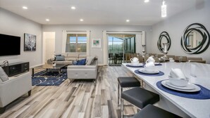 A modern kitchen with a dining area, a sofa, and a TV. - Villa in Solterra Resort 2747 (Davenport)