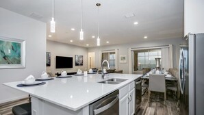 A modern kitchen with a central island, stainless steel appliances, and pendant lighting. - Villa in Solterra Resort 2747 (Davenport)