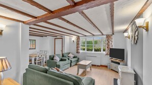 A living room with green sofas, a wooden coffee table, and a TV stand. - Conveniently located to explore all that Cornwall and Devon have to offer (SALTASH)