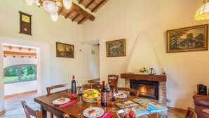 Un coin repas avec une table en bois dressée pour le repas, une cheminée et des œuvres d’art encadrées accrochées aux murs.