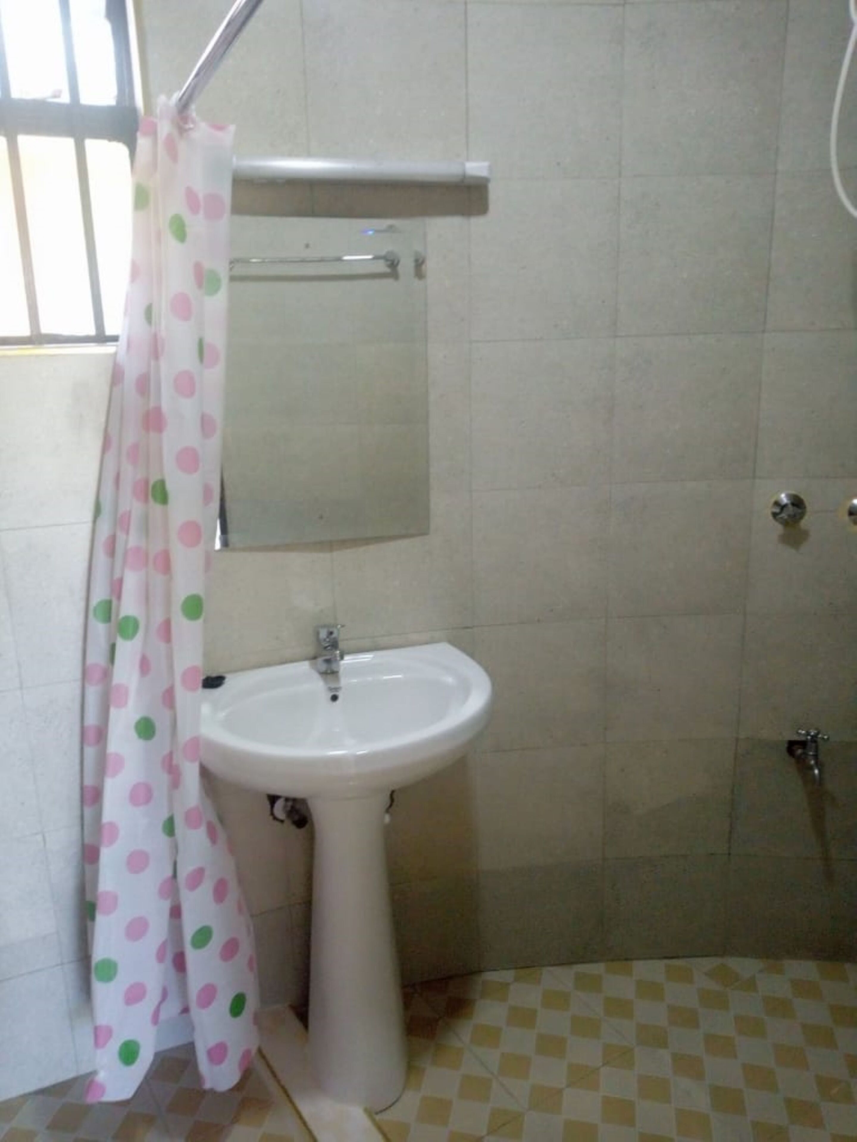 A bathroom with a white sink, a mirror above it, and a shower area.