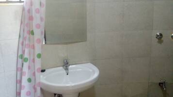 A bathroom with a white sink, a mirror above it, and a shower area.