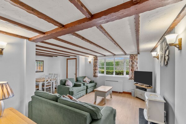 A modern living room with green sofas, a wooden coffee table, and a TV stand.