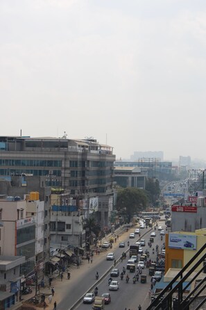 A busy urban street with multi-story buildings, vehicles, and pedestrians. - Olivia Inn And Suites (Bengaluru)
