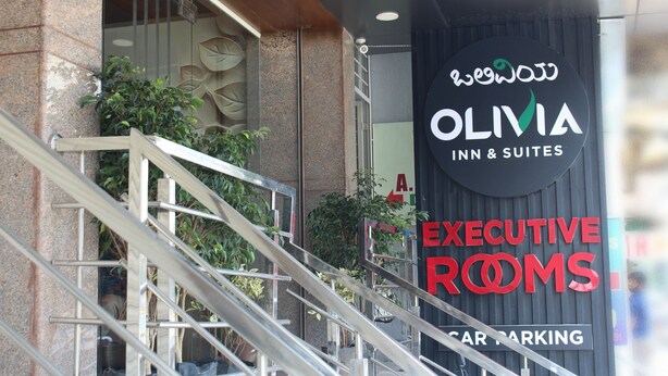The entrance to Olivia Inn & Suites with a sign for Executive Rooms and a mention of car parking. - Olivia Inn And Suites (Bengaluru)