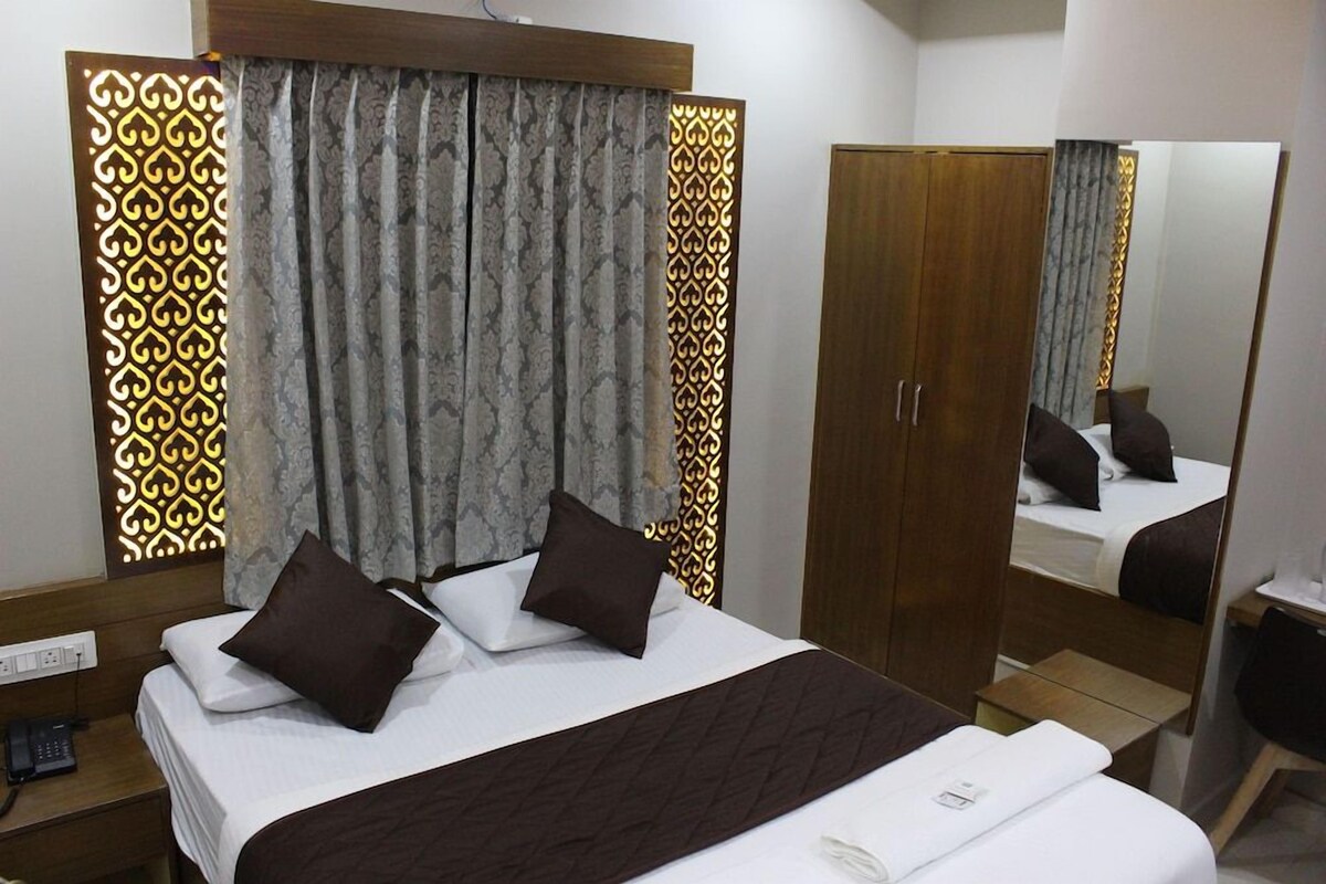 Una habitación de hotel con cama, armario, mesita de noche y espejo.
