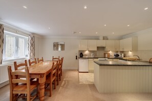 A modern kitchen with a wooden dining table and chairs, a built-in island with a sink, and white cabinetry.