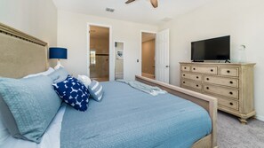 A bedroom with a bed, a dresser, a television, and a door leading to a bathroom. - Villa Close to Disney, Orlando Villa 3255 (Kissimmee)