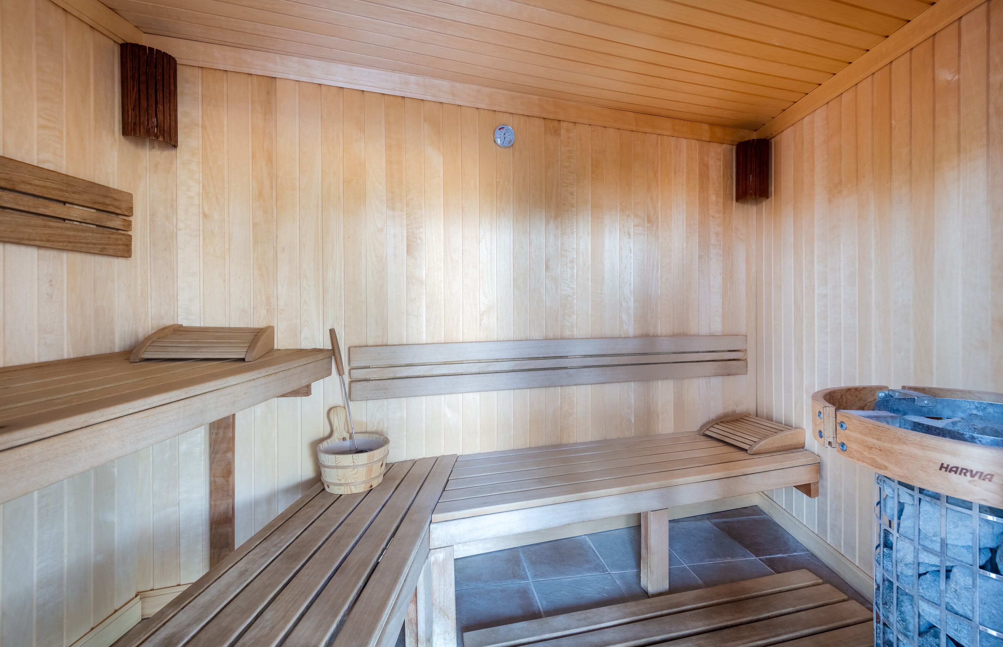 Eine Sauna mit Holzbänken und einer Steinsanitätswanne.