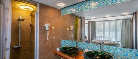 A modern bathroom with a glass-enclosed shower, two sinks with mosaic tile backs, and a large mirror.