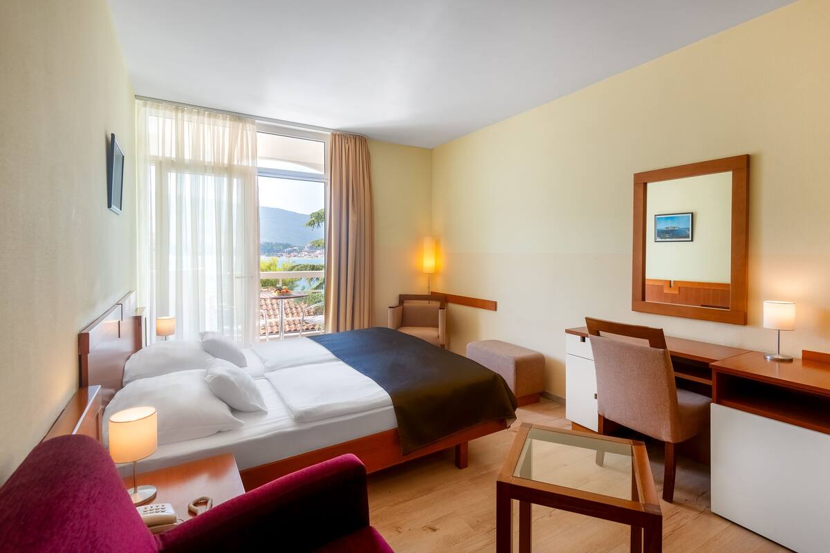 Ein Hotelzimmer mit Bett, Schreibtisch, Stuhl und Blick auf eine reizvolle Landschaft.