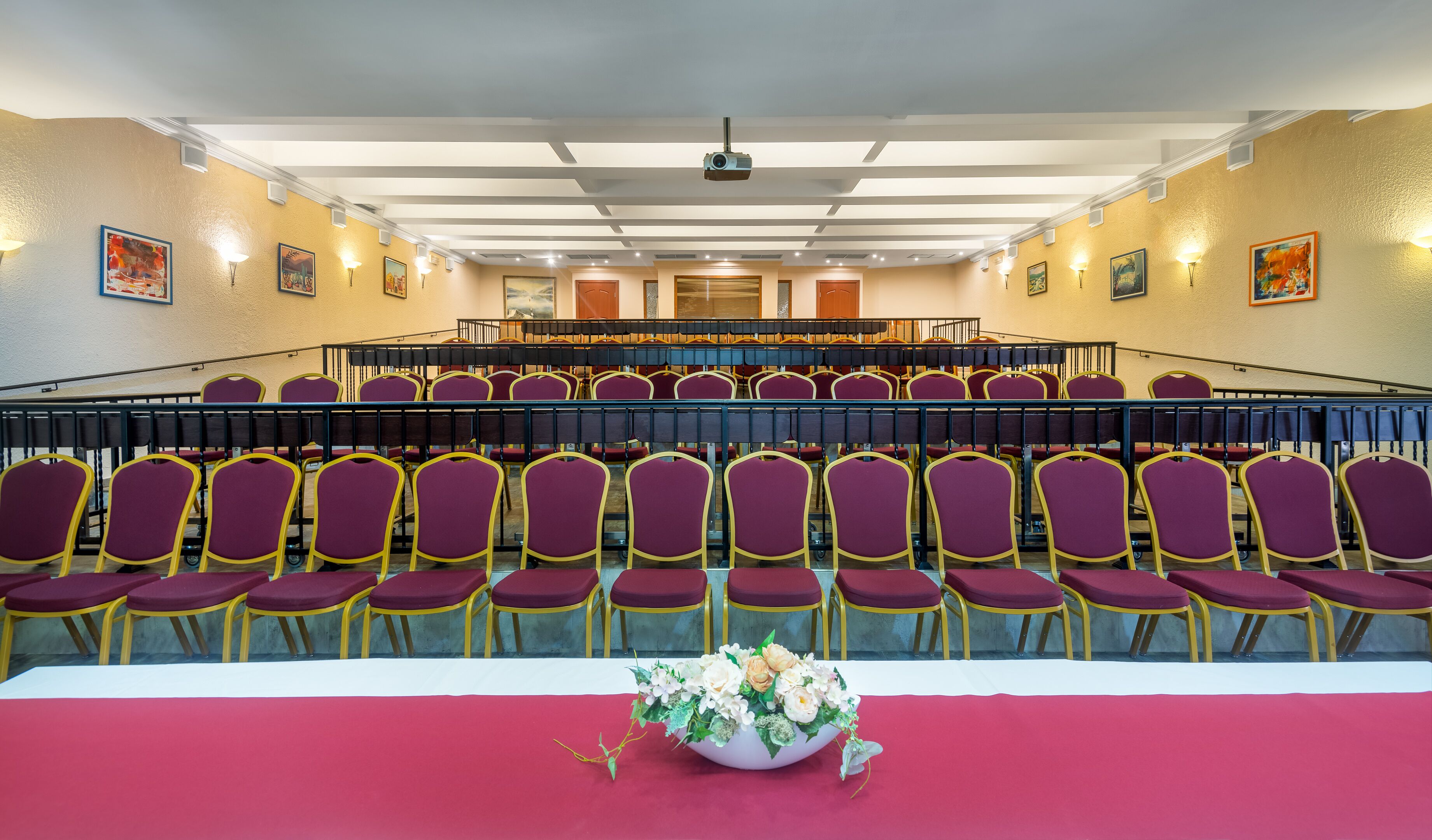 A conference room with rows of chairs, a stage, and a projector.