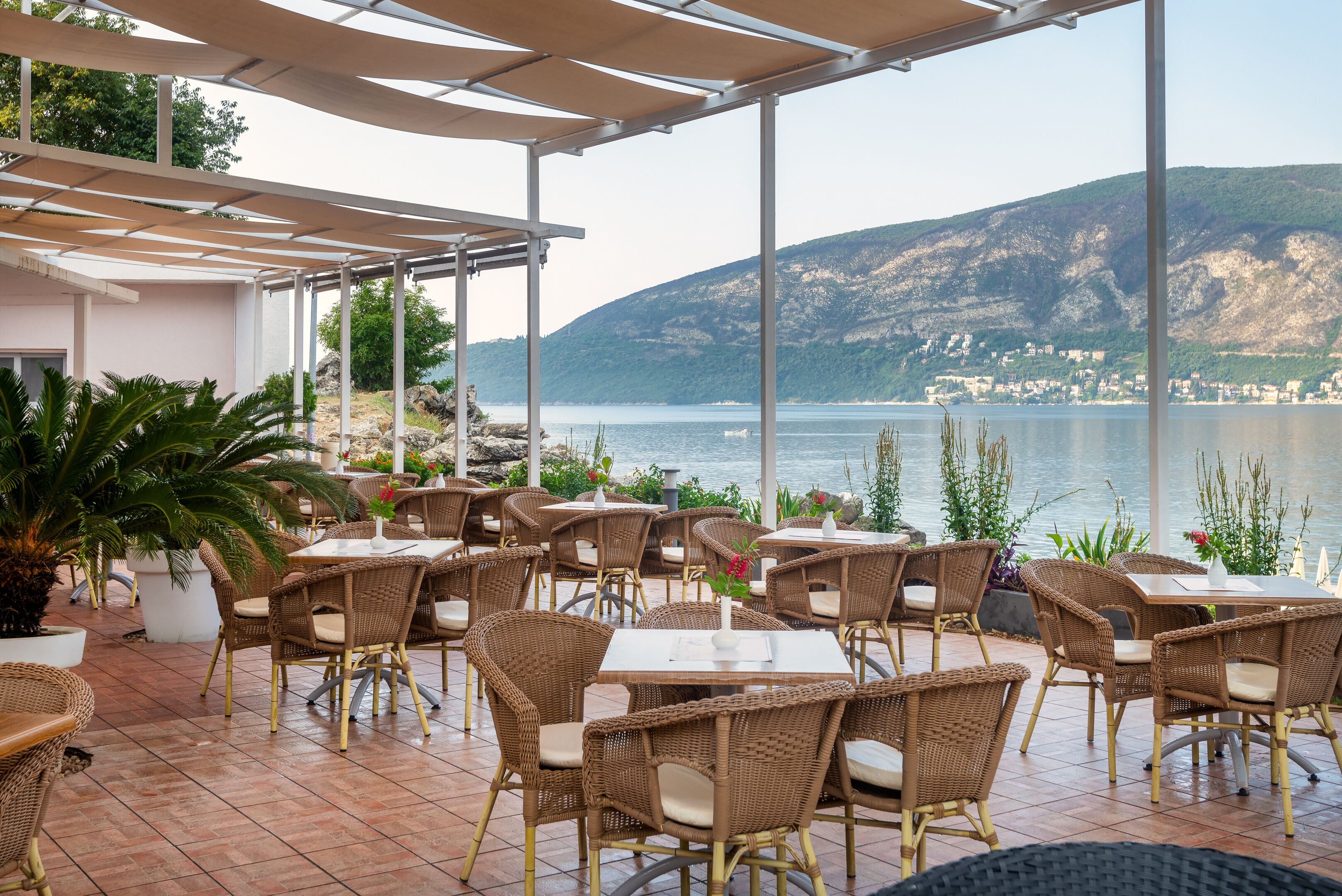 Un patio al aire libre con mobiliario de mimbre y vistas al mar y las colinas.