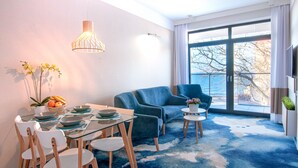 A modern living room with a dining area, large windows, and a view of the outdoors. - Apartament z widokiem na morze - Nadmorski Luksus Apartamenty (Ustronie Morskie)
