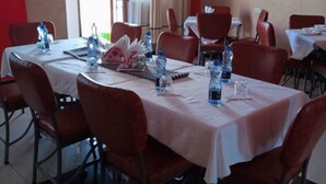 A dining area with tables set for four, each with water bottles and glasses. - MT Ararat Hotel (Nakuru)