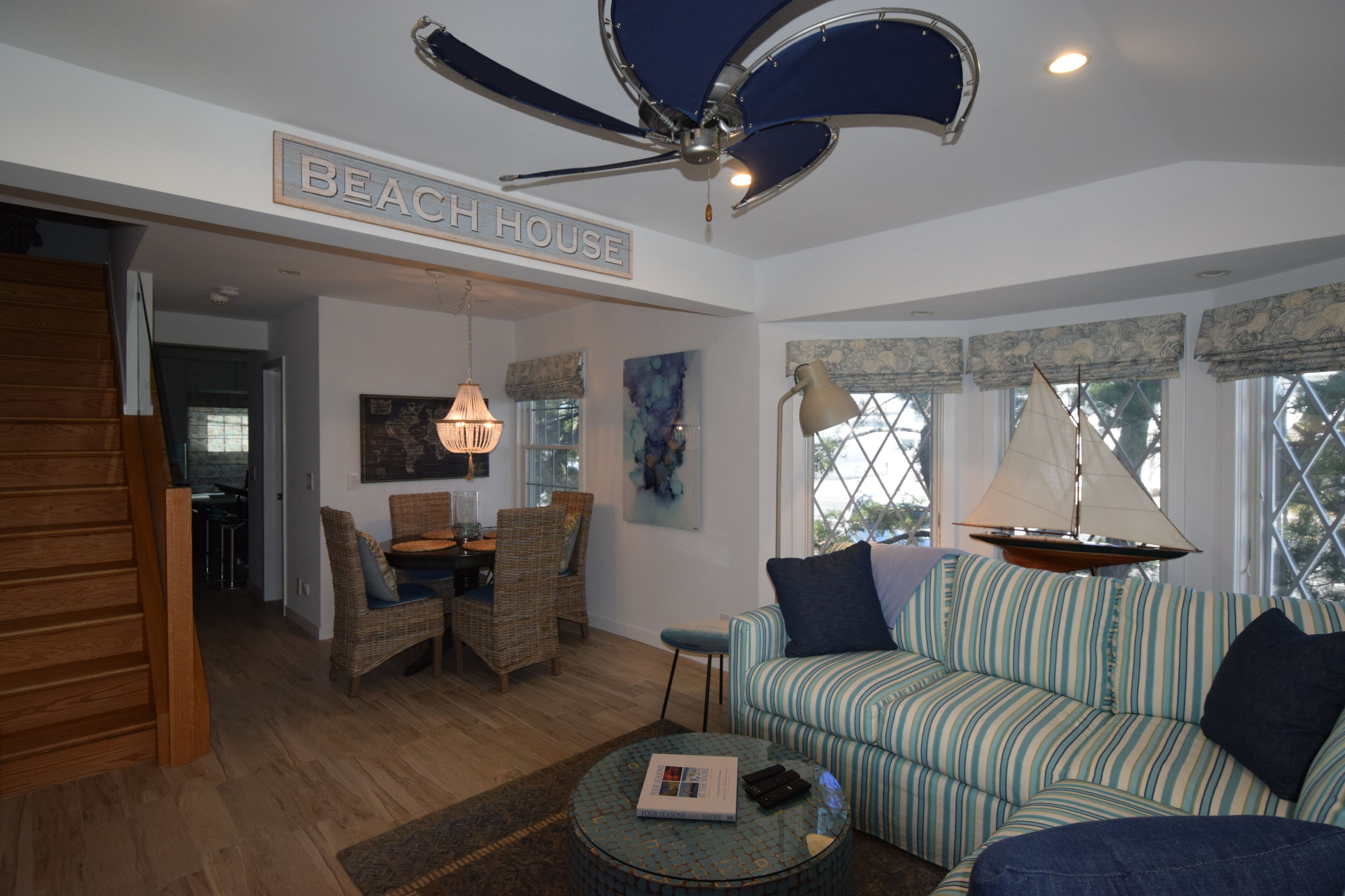 A living room with a ceiling fan, a sofa, a dining table with chairs, and a bookshelf.