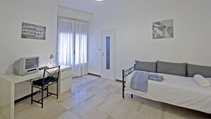 A bedroom with a bed, a desk with a computer, a chair, and two wall-mounted pictures. - Chiesarossa Holiday Home - Ideal for Families (Milan)