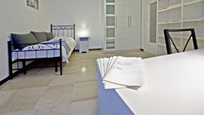 A bedroom with a bed, a nightstand, a wardrobe, and a table with papers. - Chiesarossa Holiday Home - Ideal for Families (Milan)