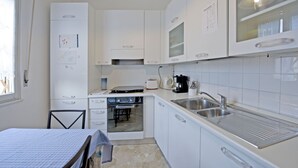 A compact kitchen with white cabinets, a built-in oven, a microwave, and a sink. - Chiesarossa Holiday Home - Ideal for Families (Milan)