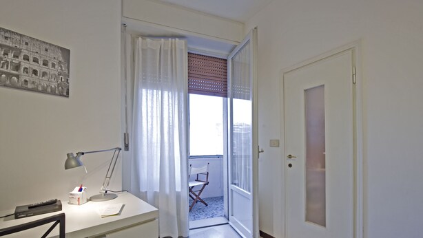 A room with a desk, a chair, a lamp, a window with curtains, and a door. - Chiesarossa Holiday Home - Ideal for Families (Milan)