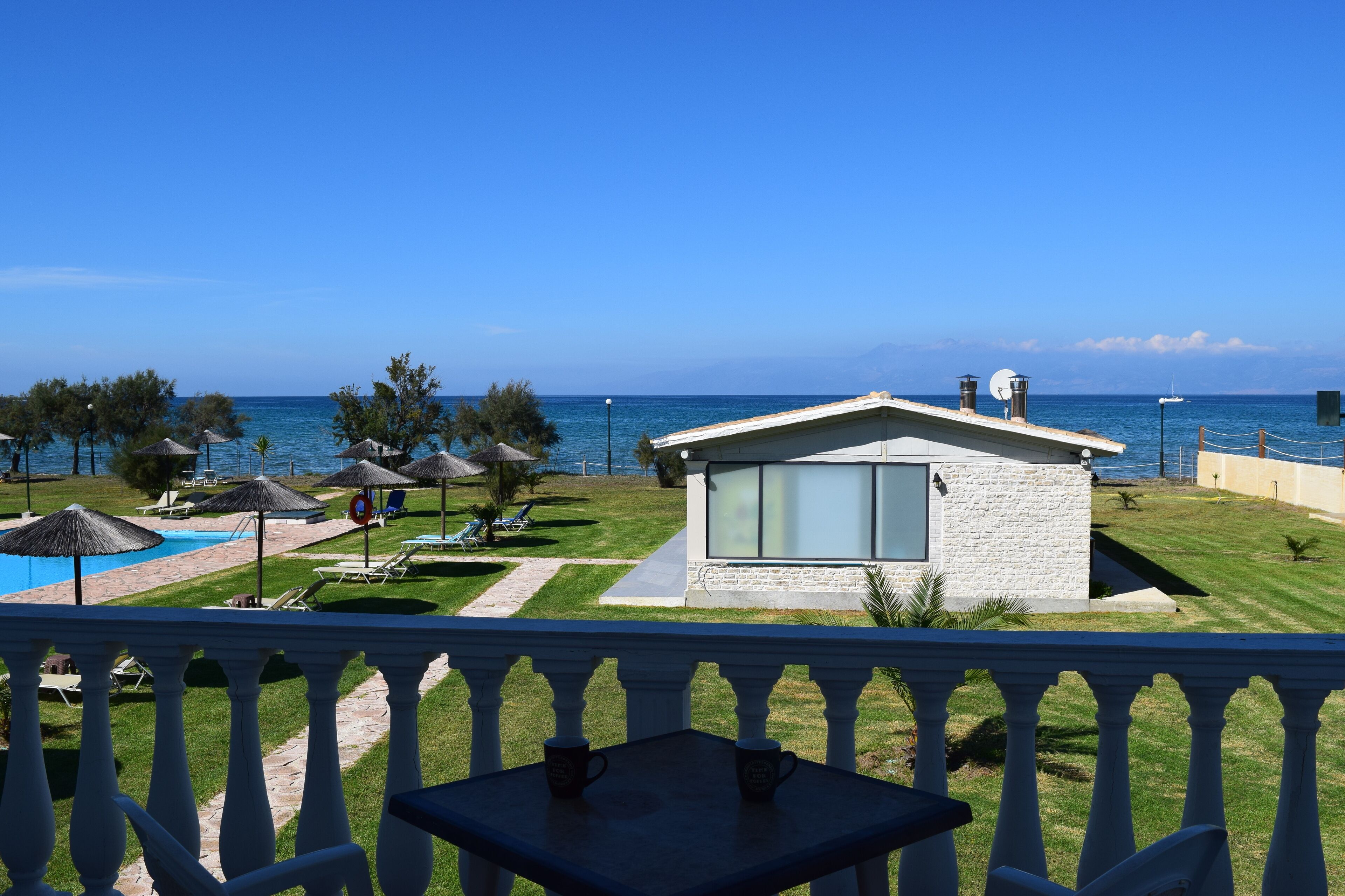 A modern building with a large glass window, a pool, and a view of the sea.