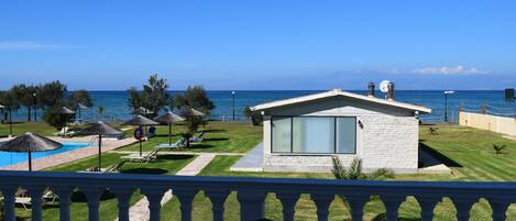 A modern building with a large glass window, a pool, and a view of the sea.