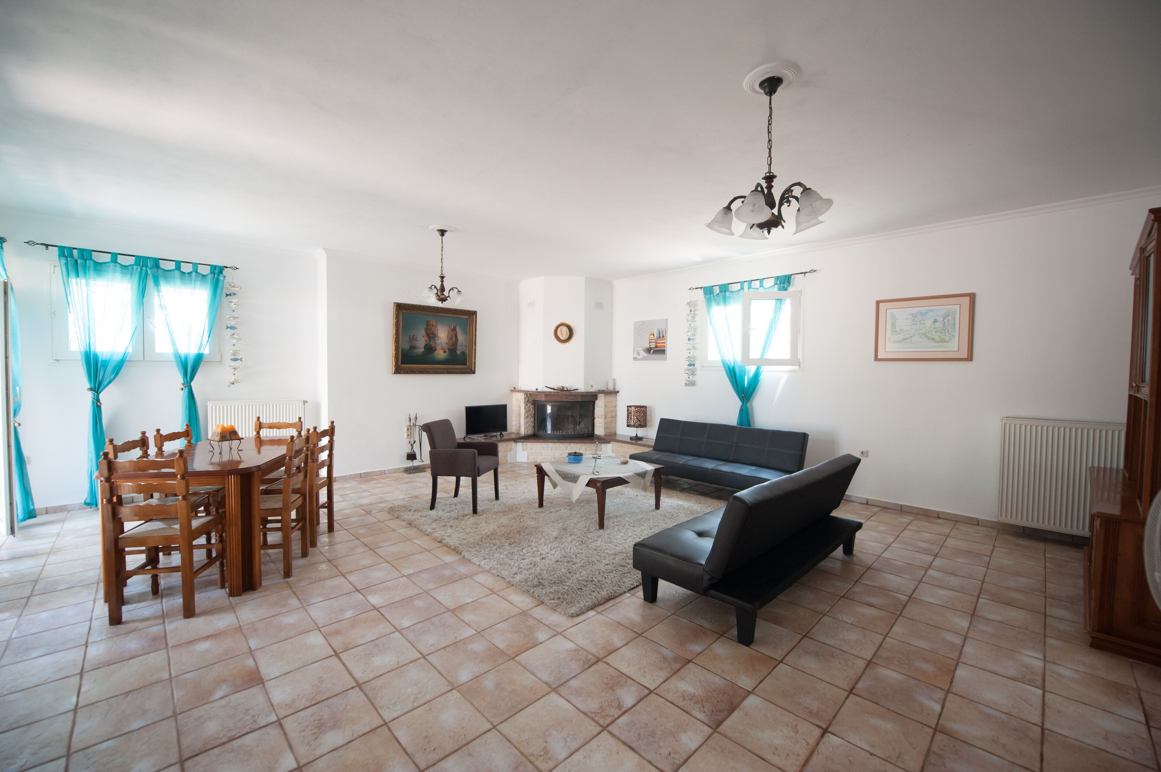 Una sala de estar con chimenea, un sofá, una mesa de comedor con sillas y un televisor.