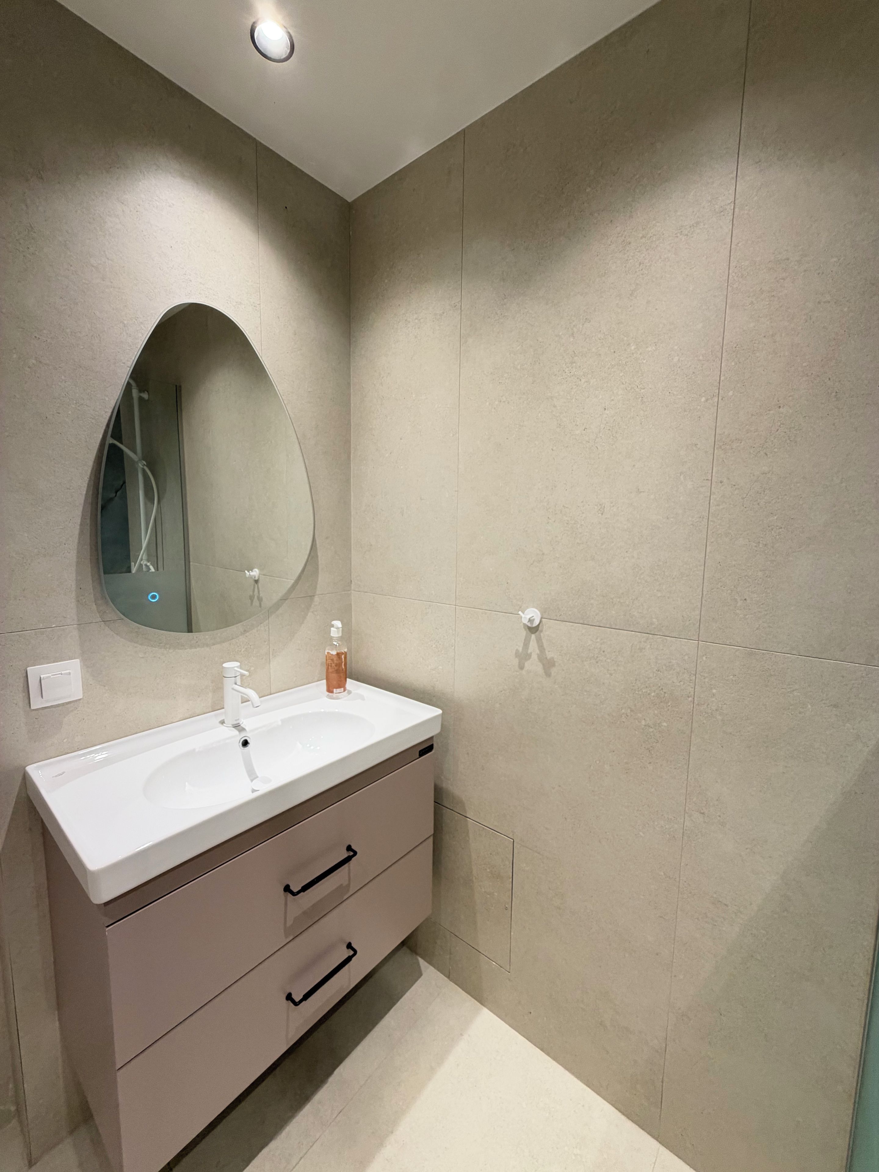 A bathroom with a white sink, a mirror, and a shower.