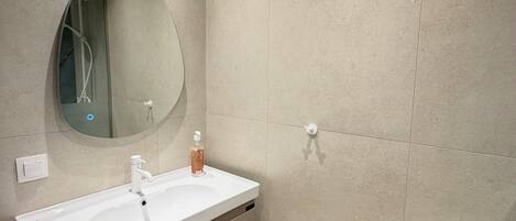 A bathroom with a white sink, a mirror, and a shower.