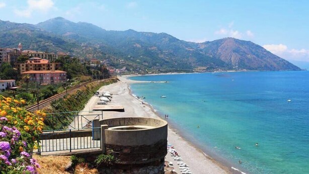 A coastal view with a beach, a concrete structure, and buildings in the background. - Room-michelangelo House, Bilo (Gioiosa Marea)