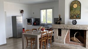 Une cuisine spacieuse avec un coin repas, une cheminée et une grande fenêtre.