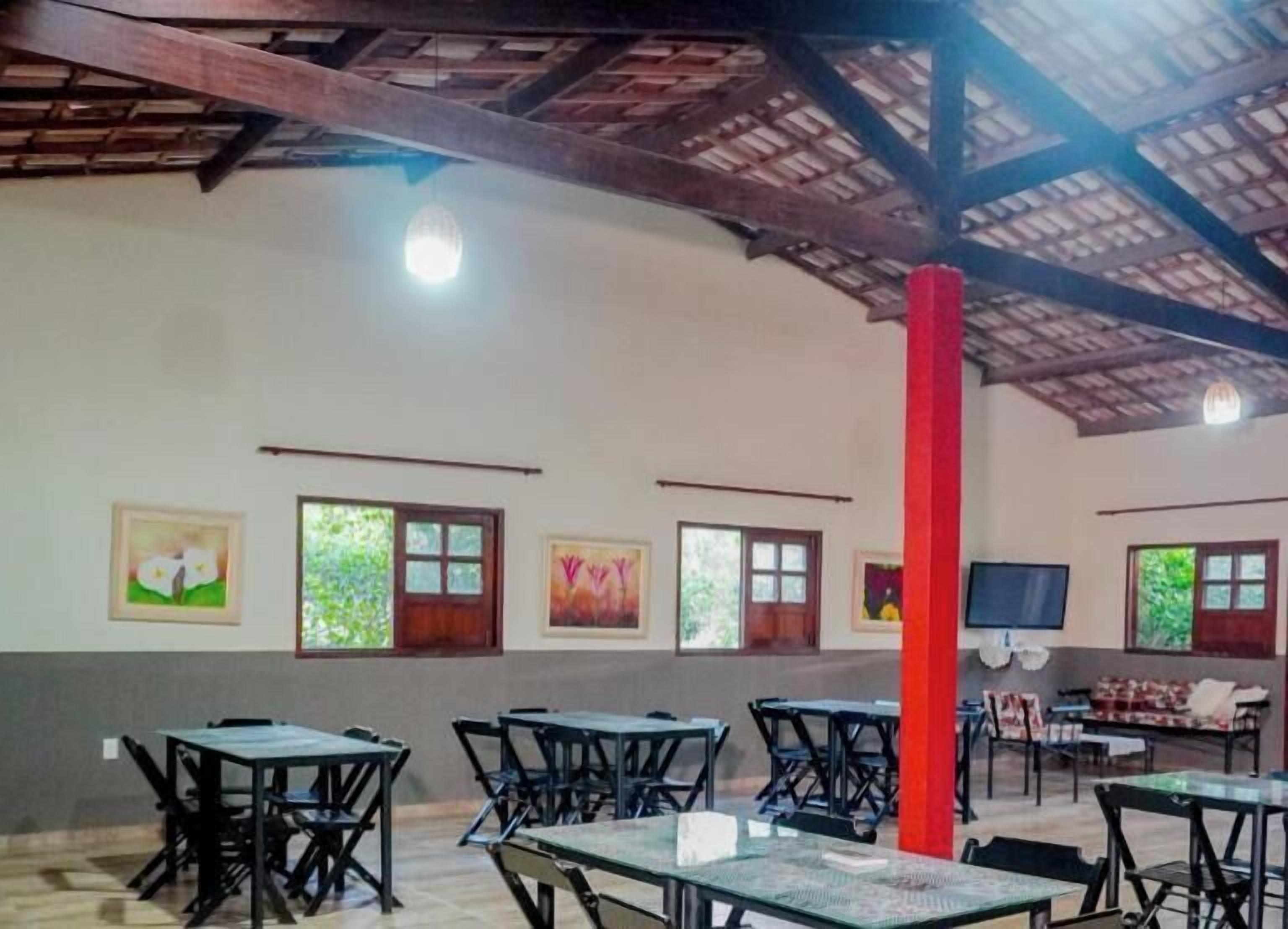 A dining area with tables and chairs, a red pillar, and artwork on the walls.