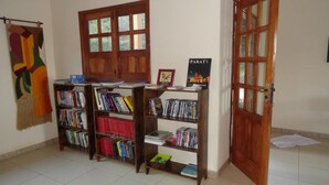 Una habitación con tres estanterías de madera llenas de libros, un tapiz en la pared y una puerta con paneles de vidrio.