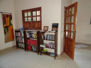 Una habitación con tres estanterías de madera llenas de libros, un tapiz en la pared y una puerta con paneles de vidrio.