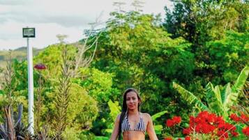 A person standing in a natural setting with greenery and rocks.
