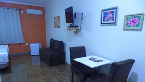 Un espacio de estar pequeño y funcional con un sofá, una mesita y un televisor instalado en la pared.