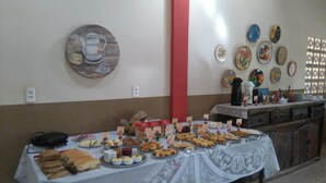 Una mesa de buffet con diversos alimentos y una cafetera en la pared.