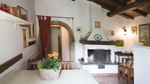 A rustic interior with a fireplace, wooden beams, and a dining area with a table and chairs. - Apartment le Scalette a Relaxing Oasis Near Florence (Vicchio)