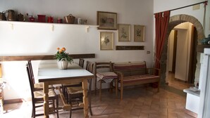 A dining area with a wooden table and chairs, a bench, and a shelf with various kitchen items. - Apartment le Scalette a Relaxing Oasis Near Florence (Vicchio)
