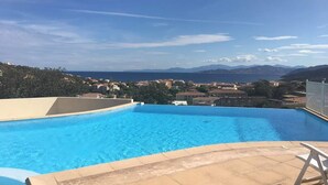 En swimmingpool med fri utsikt över havet och bergen i bakgrunden.