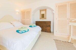 A bedroom with a bed, a wooden dresser, a mirror, and two wooden doors.